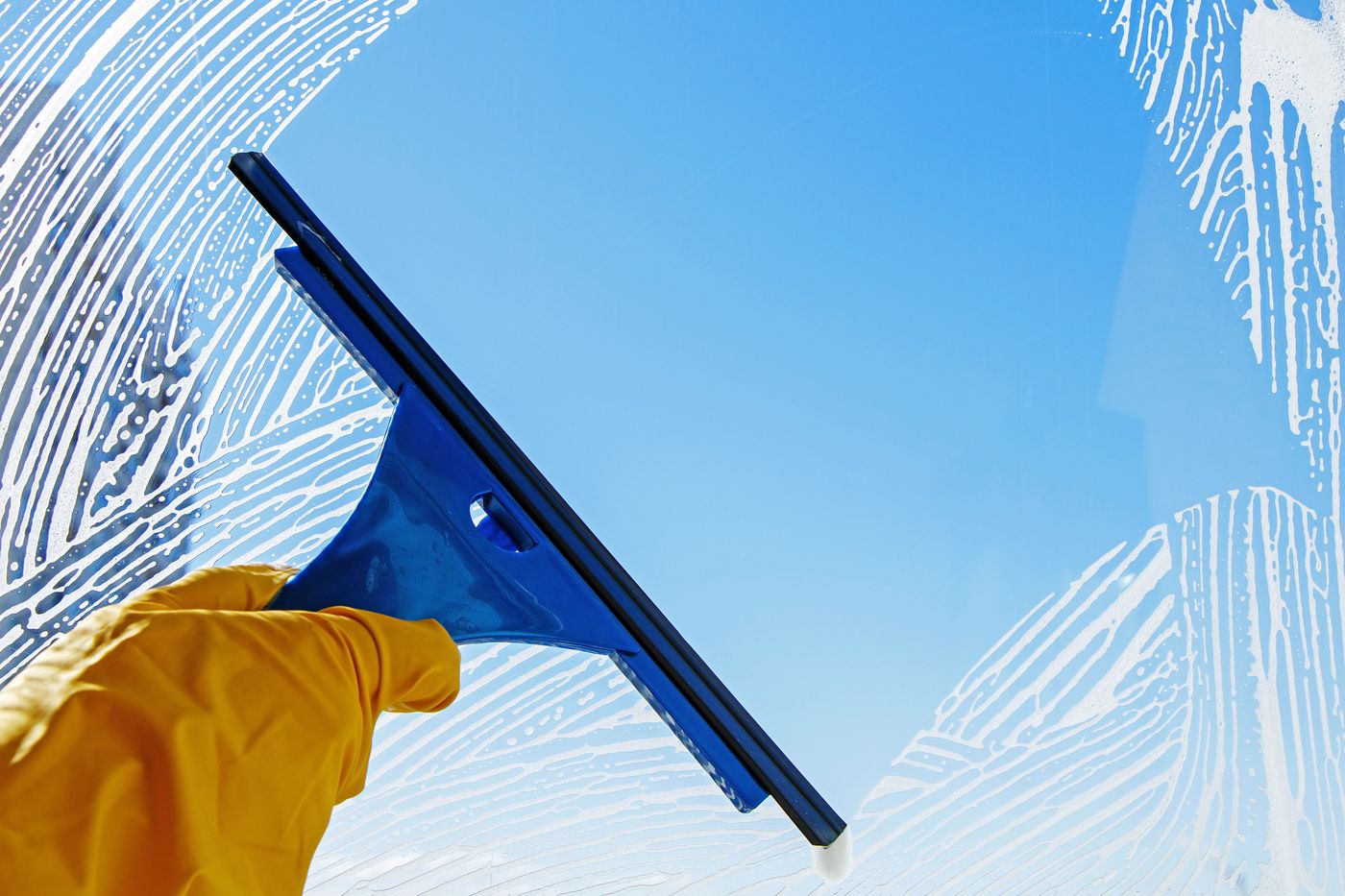 Squeegee cleaning a window against blue sky